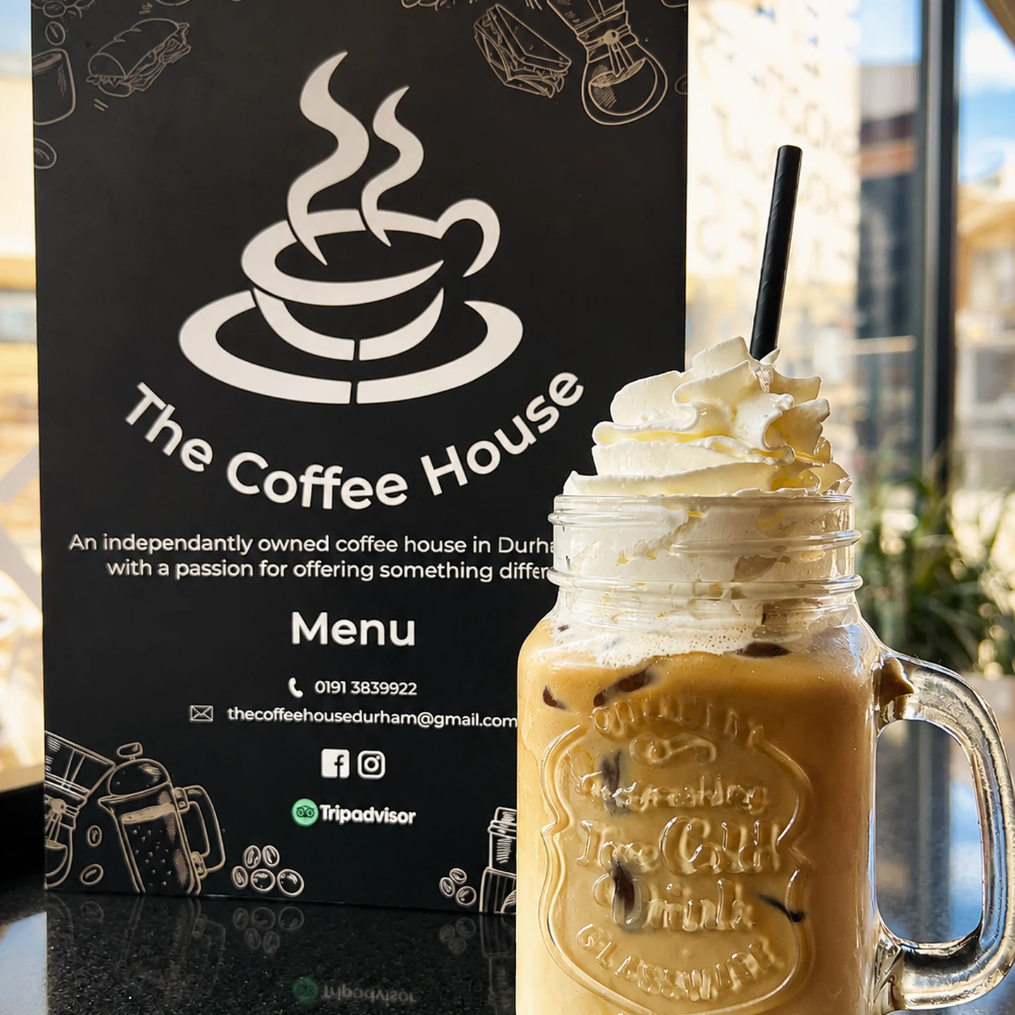 Coffee drink beside The Coffee House Durham menu sign